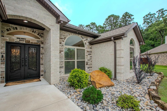 1027 Evening Sunset Cir, Redfield, AR 72132 - view of exterior entry with french doors, brick siding, roof with shingles, and stone siding