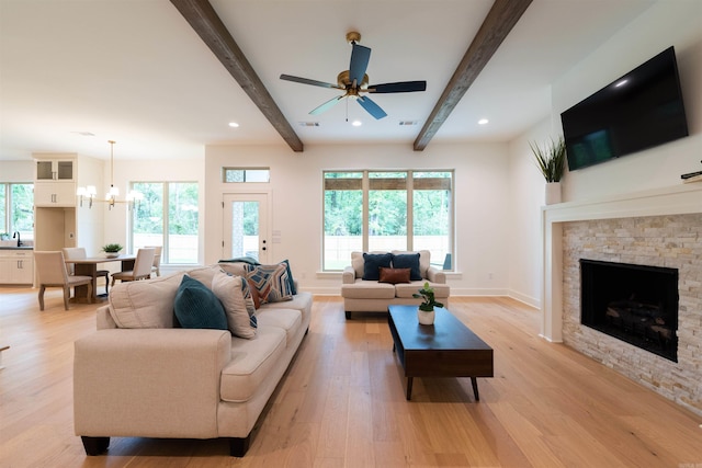 14408 Stonebrook Ln, Maumelle, AR 72113 - living room with a ceiling fan, beamed ceiling, a fireplace, a chandelier, and light wood-style flooring
