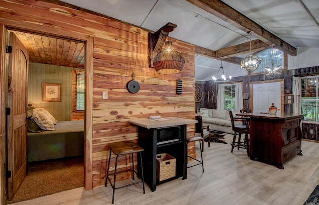 164 Roxie Ln, Greers Ferry, AR 72067 - kitchen featuring wood walls, a chandelier, a kitchen breakfast bar, light wood-style flooring, and plenty of natural light