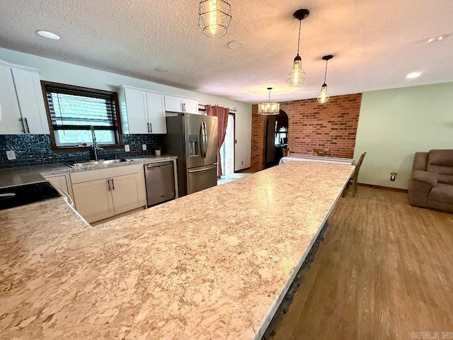1711 Lonoke Rd, Mountain Home, AR 72653 - kitchen featuring appliances with stainless steel finishes, wood finished floors, a textured ceiling, tasteful backsplash, and open floor plan