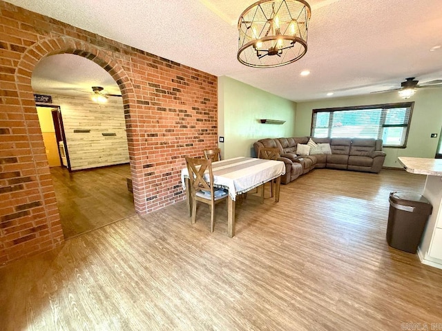 1711 Lonoke Rd, Mountain Home, AR 72653 - dining area featuring a ceiling fan, wood finished floors, brick wall, a textured ceiling, and a chandelier