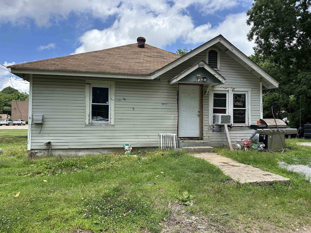 206 Center St, Harrisburg, AR 72432 - view of front facade featuring a front yard, a shingled roof, and cooling unit