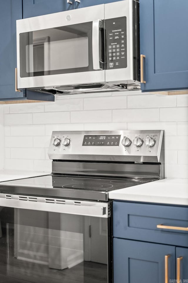 8719 Evergreen Dr, Little Rock, AR 72227 - detailed view of stainless steel appliances, blue cabinetry, tasteful backsplash, and light countertops