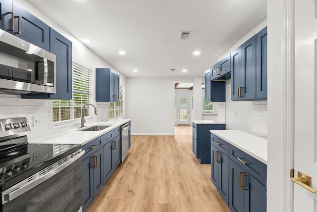 8719 Evergreen Dr, Little Rock, AR 72227 - kitchen with appliances with stainless steel finishes, blue cabinetry, backsplash, light wood-style floors, and recessed lighting