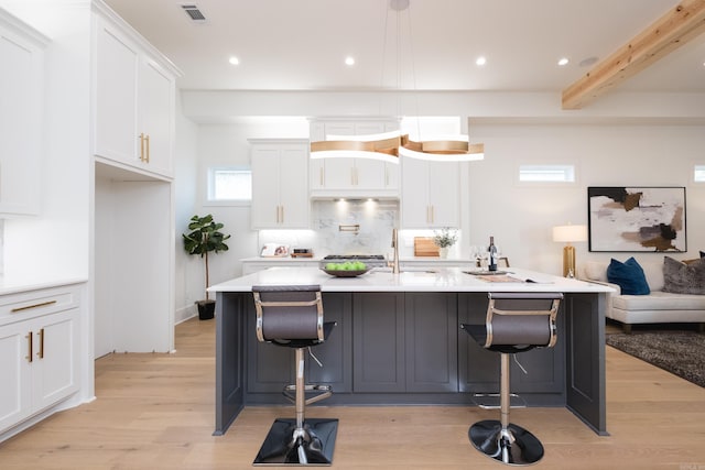 111 Mergeron Ct, Little Rock, AR 72212 - kitchen with light wood-type flooring, white cabinetry, recessed lighting, light countertops, and a kitchen bar