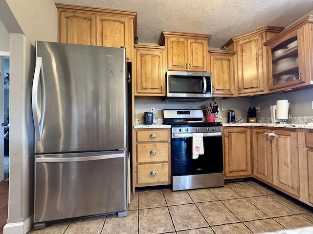 389 Plantation Cir, Melbourne, AR 72556 - kitchen featuring stainless steel appliances, light tile patterned floors, light stone counters, glass insert cabinets, and a textured ceiling