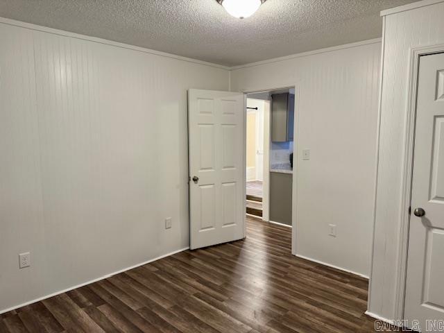 1520 S Main St, Malvern, AR 72104 - unfurnished room with dark wood-style floors, a textured ceiling, and ornamental molding