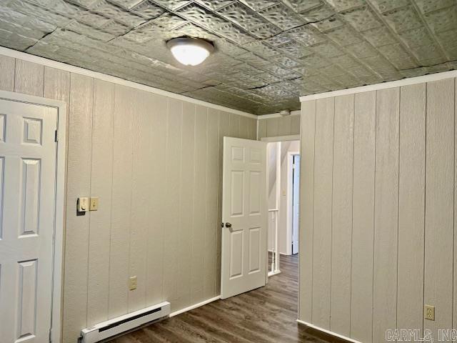 1520 S Main St, Malvern, AR 72104 - unfurnished room with a baseboard heating unit, wood walls, wood finished floors, and an ornate ceiling
