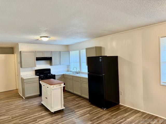 1520 S Main St, Malvern, AR 72104 - kitchen with black appliances, a textured ceiling, a kitchen island, wood finished floors, and exhaust hood