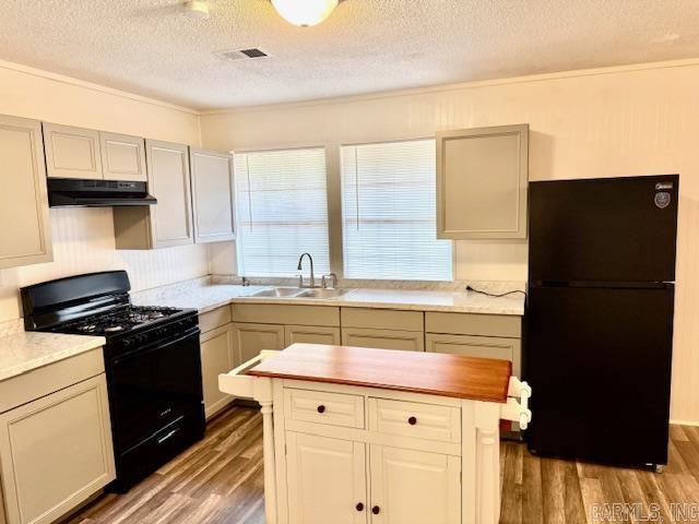 1520 S Main St, Malvern, AR 72104 - kitchen featuring black appliances, under cabinet range hood, a textured ceiling, wood finished floors, and ornamental molding