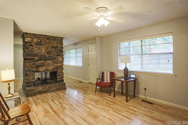42 Bradford, Little Rock, AR 72227 - sitting room with wood finished floors, a ceiling fan, a stone fireplace, and a textured ceiling