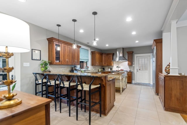 1116 Kavanaugh Blvd, Little Rock, AR 72205 - kitchen featuring wall chimney range hood, backsplash, brown cabinets, a peninsula, and stone countertops