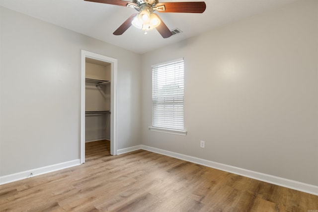 70 Peach St, Austin, AR 72007 - unfurnished bedroom featuring light wood-style floors, a closet, ceiling fan, and a walk in closet