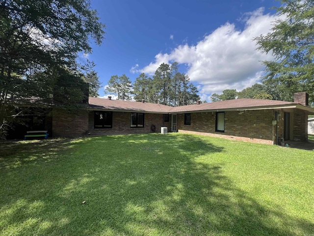 114 Mark Cir, Monticello, AR 71655 - back of property with a lawn and a chimney
