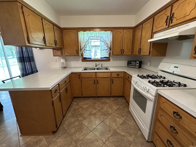 504 Case St, Heber Springs, AR 72543 - kitchen with white gas range, under cabinet range hood, a peninsula, brown cabinets, and light countertops