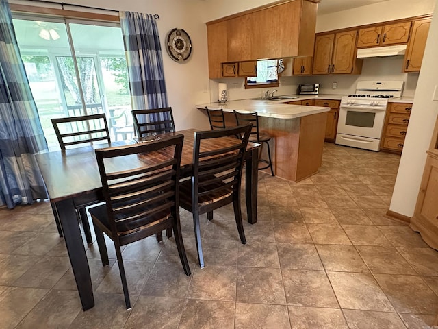 504 Case St, Heber Springs, AR 72543 - kitchen featuring gas range gas stove, under cabinet range hood, a peninsula, light countertops, and brown cabinetry