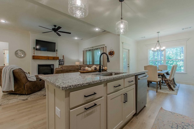 18508 Parkway Pines Dr, Bauxite, AR 72011 - kitchen featuring stainless steel dishwasher, light wood-style floors, a glass covered fireplace, light stone counters, and ornamental molding