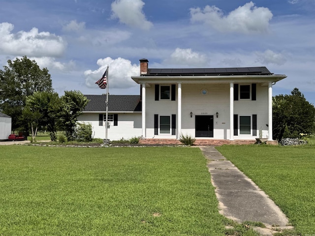 2025 Fairway St, Stuttgart, AR 72160 - greek revival house featuring a front lawn, a chimney, a porch, and roof mounted solar panels
