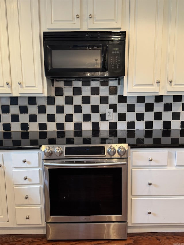 2025 Fairway St, Stuttgart, AR 72160 - kitchen with black microwave, stainless steel range with electric cooktop, dark countertops, white cabinets, and decorative backsplash