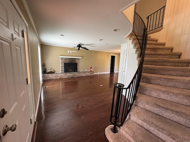 2025 Fairway St, Stuttgart, AR 72160 - unfurnished living room featuring ornamental molding, a brick fireplace, stairs, wood finished floors, and a ceiling fan