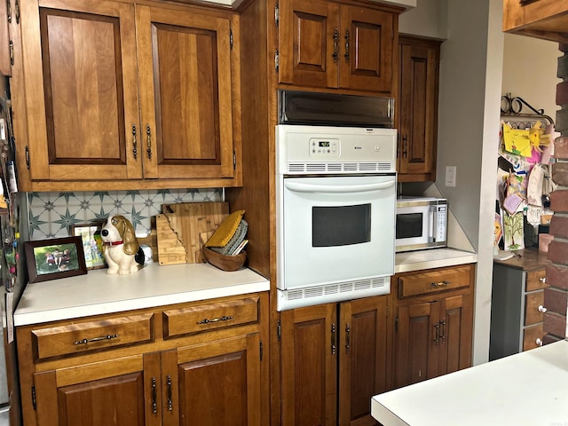 102 Mockingbird Ln, Arkadelphia, AR 71923 - kitchen with white oven, light countertops, stainless steel microwave, brown cabinetry, and backsplash
