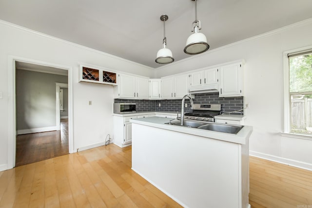 4106 C St, Little Rock, AR 72205 - kitchen with appliances with stainless steel finishes, decorative backsplash, under cabinet range hood, hanging light fixtures, and crown molding