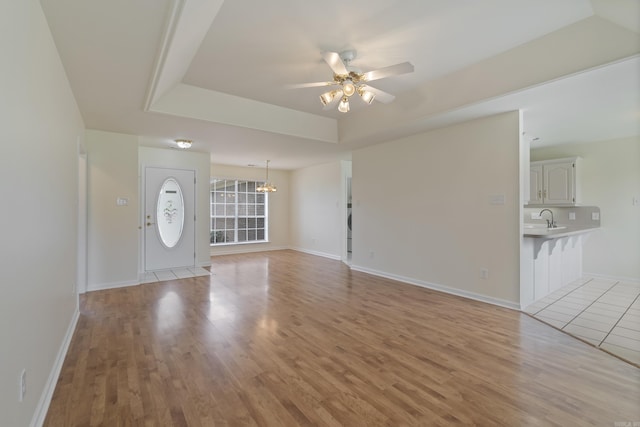 unfurnished living room with a ceiling fan, light wood-style flooring, and a chandelier