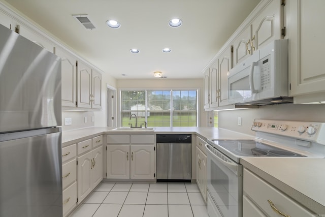 kitchen featuring appliances with stainless steel finishes, recessed lighting, light countertops, light tile patterned flooring, and white cabinetry