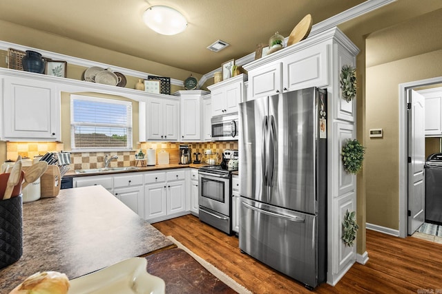 27 Magnolia Ln, Ward, AR 72176 - kitchen featuring stainless steel appliances, dark wood-style flooring, white cabinetry, decorative backsplash, and dark countertops