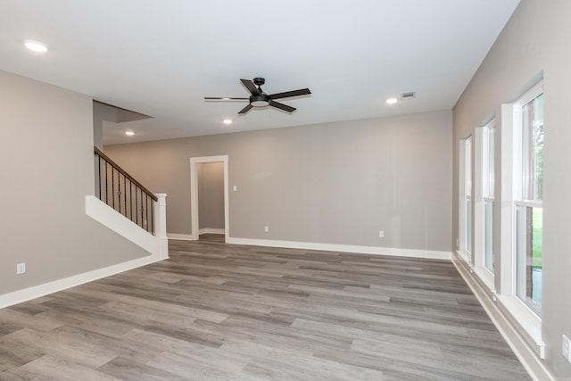 empty room with plenty of natural light, a ceiling fan, wood finished floors, stairway, and recessed lighting