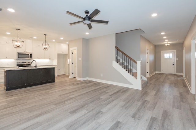 kitchen featuring stainless steel appliances, open floor plan, white cabinetry, recessed lighting, and light countertops