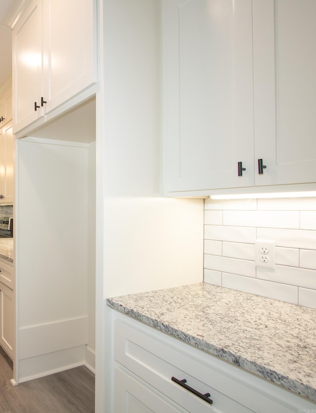 kitchen featuring wood finished floors, light stone countertops, and white cabinetry