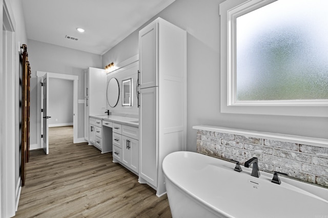 1500 Haley Ln, Conway, AR 72034 - full bathroom with double vanity, a soaking tub, wood finished floors, and decorative backsplash