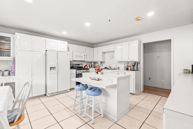 114 Woodiel Cir, Cabot, AR 72023 - kitchen with white appliances, light countertops, white cabinetry, a kitchen breakfast bar, and light tile patterned floors