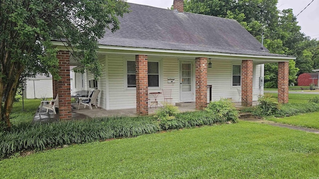 121 W 5th St, Rector, AR 72461 - view of front facade with a porch, a front yard, a chimney, and a shingled roof