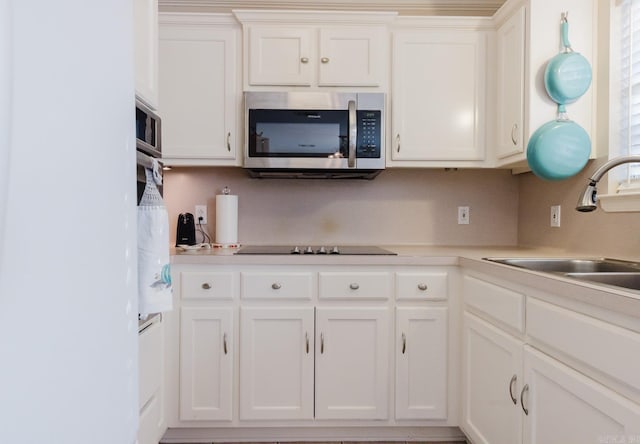 1304 Winbourne Dr, North Little Rock, AR 72116 - kitchen featuring stainless steel microwave, black electric stovetop, white cabinetry, and light countertops