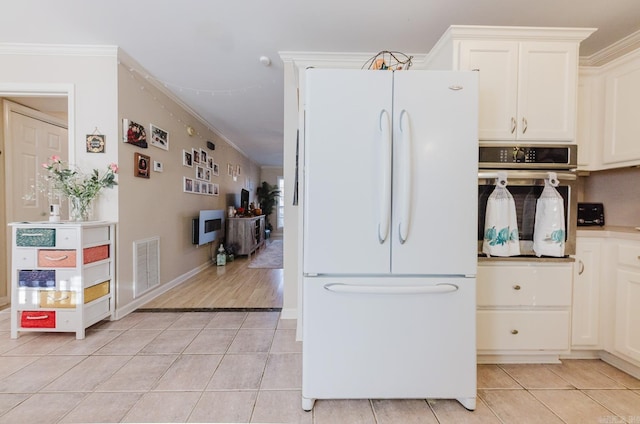 1304 Winbourne Dr, North Little Rock, AR 72116 - kitchen featuring freestanding refrigerator, light tile patterned flooring, ornamental molding, oven, and white cabinetry