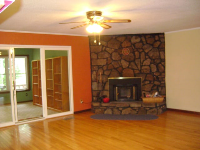 405 Fairway Dr, Horseshoe Bend, AR 72512 - unfurnished living room featuring a ceiling fan, wood finished floors, crown molding, and a stone fireplace