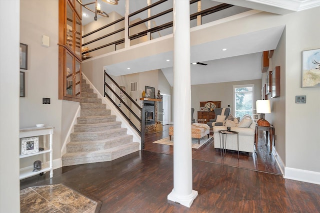 15355 Pleasant Grove Ln, Harrisburg, AR 72432 - staircase featuring wood finished floors, ornate columns, a lit fireplace, and a towering ceiling