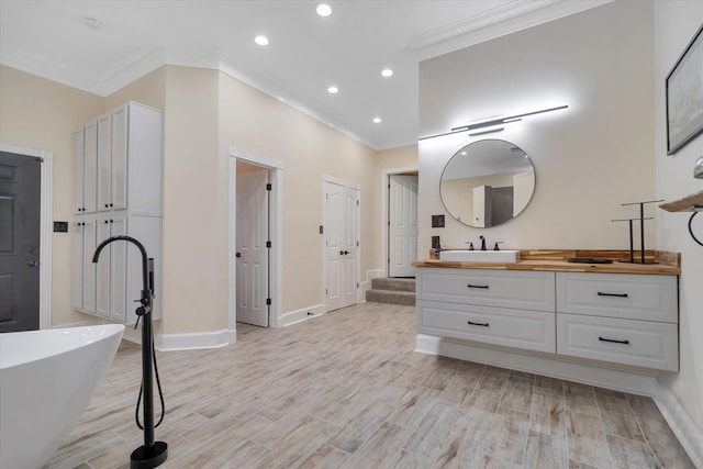 15355 Pleasant Grove Ln, Harrisburg, AR 72432 - bathroom with crown molding, vanity, a freestanding tub, recessed lighting, and wood finished floors