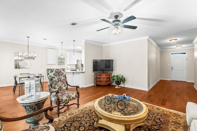 living area with wood finished floors, a ceiling fan, crown molding, and a chandelier