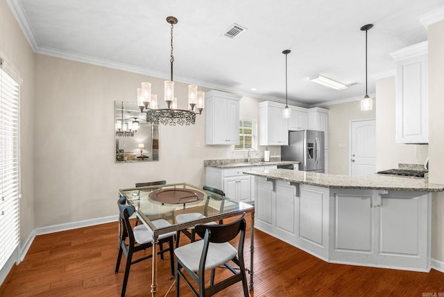 kitchen featuring stainless steel appliances, white cabinets, a peninsula, dark wood-type flooring, and ornamental molding