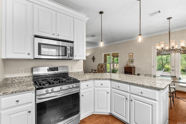 kitchen with stainless steel appliances, a peninsula, a chandelier, light wood-style floors, and ornamental molding