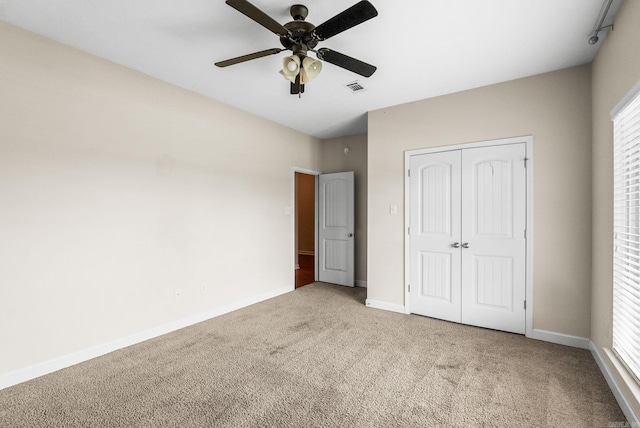 unfurnished bedroom with carpet flooring, a closet, ceiling fan, and multiple windows