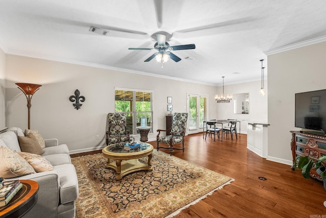 living area featuring a ceiling fan, ornamental molding, a chandelier, and dark wood-style flooring