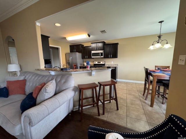 kitchen with stainless steel appliances, open floor plan, a chandelier, arched walkways, and light tile patterned floors
