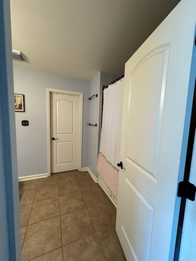 hallway featuring tile patterned flooring and baseboards