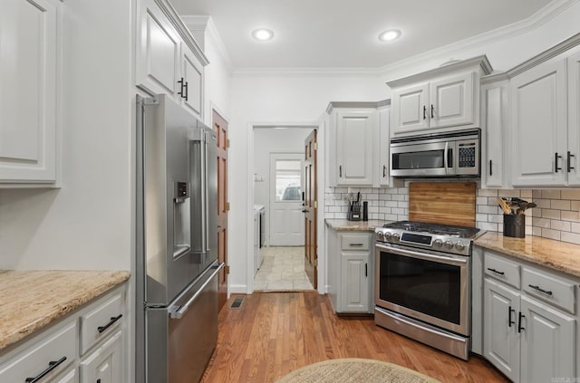 2716 Juniper Dr, Benton, AR 72015 - kitchen featuring stainless steel appliances, independent washer and dryer, wood finished floors, crown molding, and tasteful backsplash
