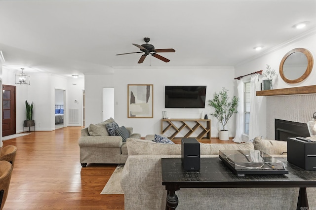 2716 Juniper Dr, Benton, AR 72015 - living room with ornamental molding, wood finished floors, a fireplace, a chandelier, and ceiling fan