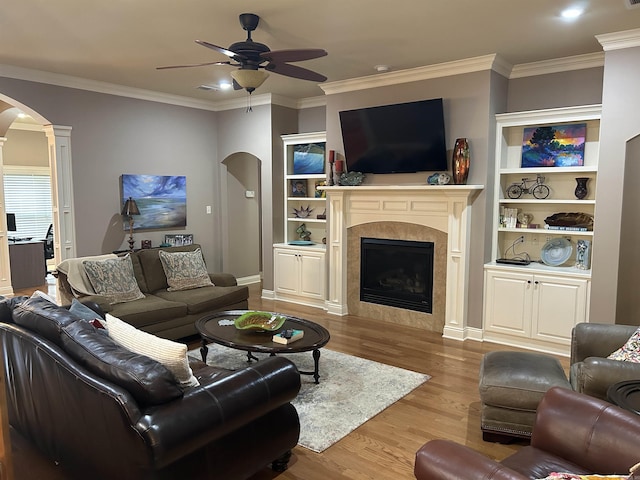 2205 Vermont St, Conway, AR 72034 - living room with arched walkways, a ceiling fan, wood finished floors, a tiled fireplace, and ornamental molding